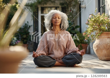 Photo of a senior woman in a yoga pose on a patio, meditating outdoors Photo of a senior woman in a yoga pose on a patio, meditating outdoors 128289563