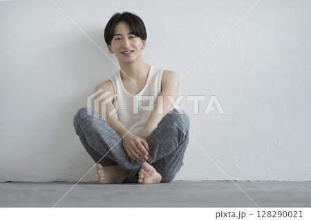 カメラ目線で座る笑顔の20代の男性　メンズビューティーイメージ　ポートレート 128290021