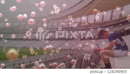 Image of 3d coronavirus cells floating over rugby player holding rugby ball on empty stadium Image of 3d coronavirus cells floating over rugby player holding rugby ball on empty stadium 128290903