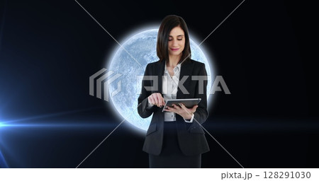 Image of woman using tablet over planet earth with glowing spot of light 128291030