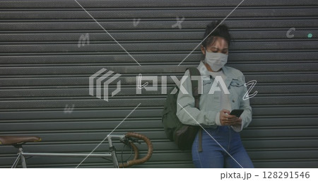 Digital composition of multiple alphabets falling against woman wearing face mask using smartphone Digital composition of multiple alphabets falling against woman wearing face mask using smartphone 128291546
