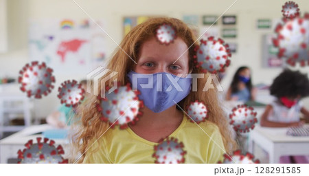 Image of floating covid 19 cells and schoolgirl in class wearing face mask 128291585