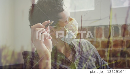 Tall grass moving in the wind against caucasian man wearing face mask holding pen at office Tall grass moving in the wind against caucasian man wearing face mask holding pen at office 128291644