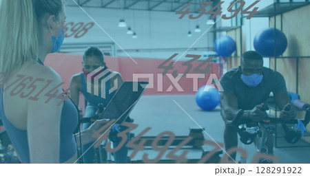 Image of numbers changing over female instructor, woman and man in face masks on bikes in gym 128291922