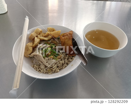 Bowl of Asian style minced meat with vegetables, fried pork, and crispy pork rinds, served with bowl of clear soup on stainless steel table, simple and appetizing meal, casual dining setting Bowl of Asian style minced meat with vegetables, fried pork, and crispy pork rinds, served with bowl of clear soup on stainless steel table, simple and appetizing meal, casual dining setting 128292209