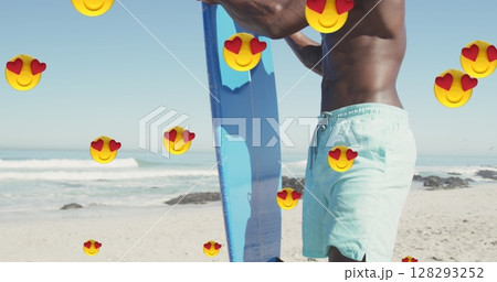 Multiple heart eyes emojis floating against african american man with surfboard on the beach 128293252