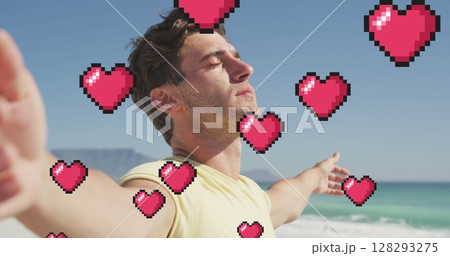 Image of heart icons over man with eyes closed and arms stretched on beach 128293275