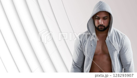Athletic man in gray hoodie focusing on fitness goals against abstract background 128293907