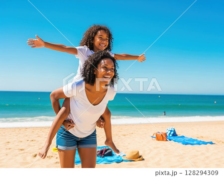 Mother and daughter play by shore, smiling and enjoying freedom of summer vacation under bright sun 128294309
