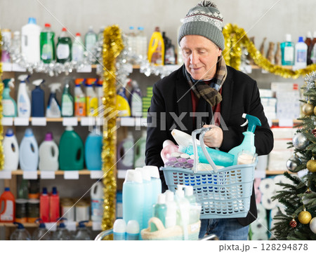 On New Year Eve, senior man with filled basket household chemistry looking for something 128294878