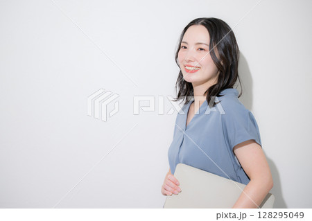 白背景(白バック)でパソコンを持つ爽やかな春夏の半袖ビジネス(オフィスカジュアル)の女性 白背景(白バック)でパソコンを持つ爽やかな春夏の半袖ビジネス(オフィスカジュアル)の女性 128295049