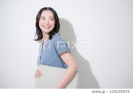 白背景(白バック)でパソコンを持つ爽やかな春夏の半袖ビジネス(オフィスカジュアル)の女性 128295055