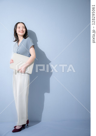 水色背景でパソコンを持つ爽やかな春夏の半袖ビジネス(オフィスカジュアル)の女性　リクルート 128295061