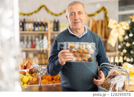 Elderly man chooses panellets at grocery store Elderly man chooses panellets at grocery store 128295078