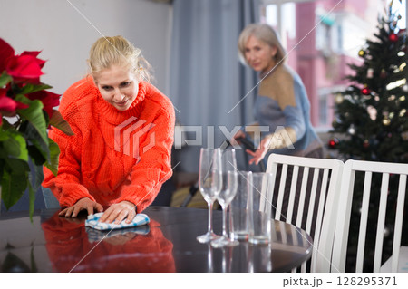 Woman cleaning table with rag at home before christmas Woman cleaning table with rag at home before christmas 128295371