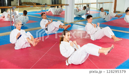 Men and women in kimono doing crunches in gym Men and women in kimono doing crunches in gym 128295379