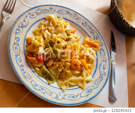 Close up of tasty warm pasta with seafood at plate on table 128295422