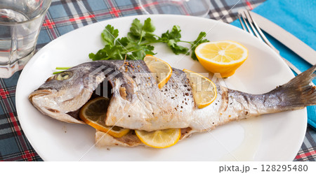 Top view of whole dorada baked with lemon served at plate with greens Top view of whole dorada baked with lemon served at plate with greens 128295480