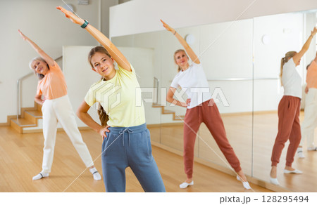 Teenage girl doing bending sideways with her family during fitness training 128295494