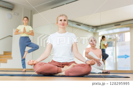 Woman practicing yoga with family in studio 128295995