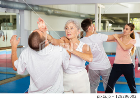 Elderly woman is training with man on self-defense course in gym 128296002