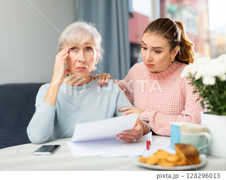 Upset mother and daughter with financial papers Upset mother and daughter with financial papers 128296013