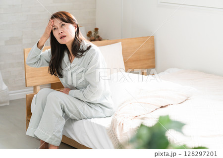 起きてベッドの上で悪寒を訴える女性 128297201