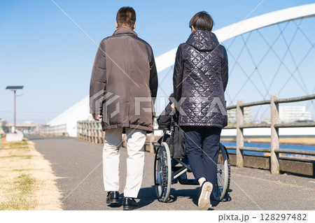 車椅子を押して散策をする親子 車椅子を押して散策をする親子 128297482