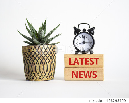 Latest News symbol. Concept words Latest News on wooden blocks. Beautiful white background with alarm clock and succulent plant. Business and Latest News concept. Copy space. 128298460
