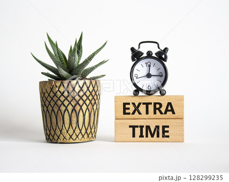 Extra time symbol. Concept word Extra time on wooden blocks. Beautiful white background with alarm clock and succulent plant. Business and Extra time concept. Copy space 128299235