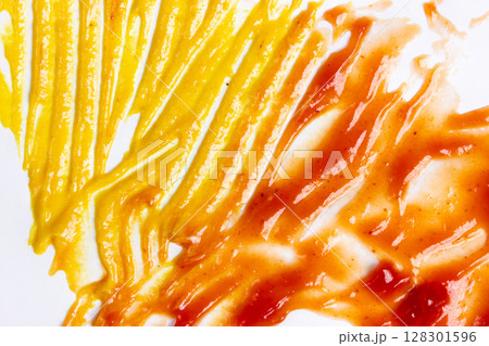 Close-up of mustard and ketchup smeared on a surface. 128301596