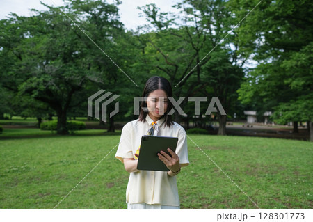 森林の中でタブレットを見る女性 128301773