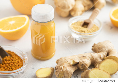 Immune orange and turmeric energy shot drink with ginger root and turmeric powder on light. 128302754