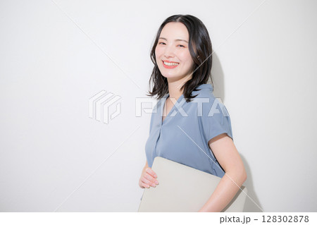 白背景(白バック)でパソコンを持つ爽やかな春夏の半袖ビジネス(オフィスカジュアル)の女性 128302878