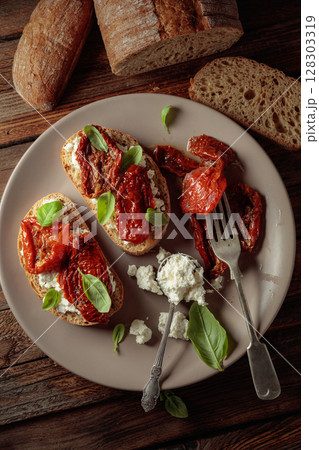 Ciabatta with sun dried tomatoes in olive oil, ricotta, and basil. 128303319