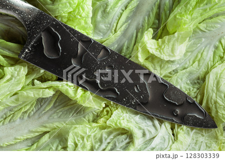 New kitchen knife with water drops on a fresh Chinese cabbage leaves. New kitchen knife with water drops on a fresh Chinese cabbage leaves. 128303339