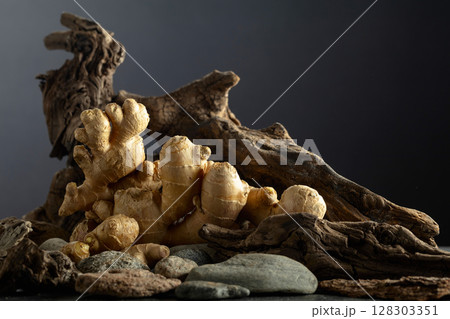 Ginger root with old snags and stones on a black background. 128303351