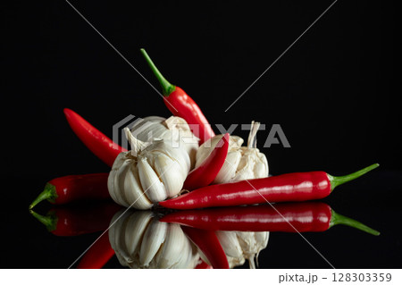 Garlic bulbs and red chili peppers on a black background. 128303359