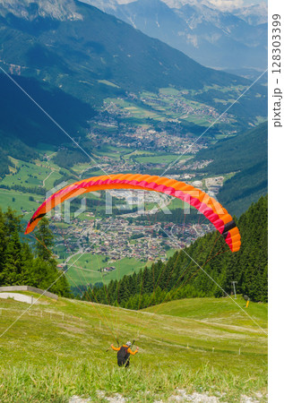 Colorful paraglider launching above Alpine valley, scenic summer mountain view. High quality photo 128303399