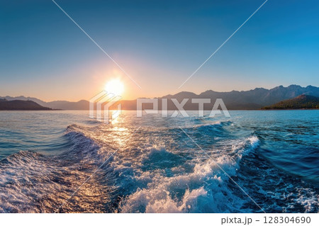 Realistic photo of the sea surface with a blue color and smooth waves, with the sun rising 128304690