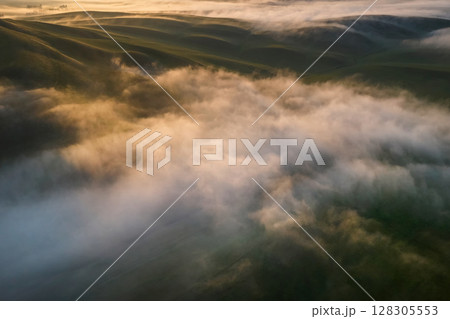 Aerial view thick morning clouds over a hilly valley 128305553