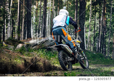 Off-road motorcyclist riding through forest path, captured from behind 128305977