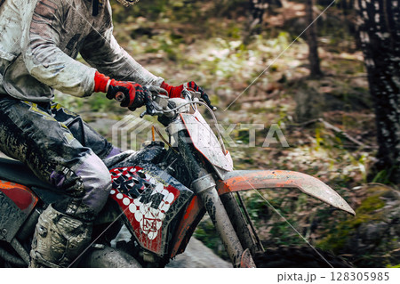 Close-up enduro rider on bike during an off-road race 128305985