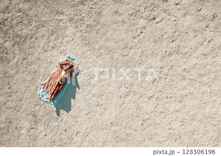 top view of a woman sunbathing on the beach 128306196