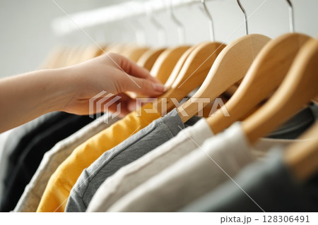 A woman hand is picking up t shirts from the rack A woman hand is picking up t shirts from the rack 128306491