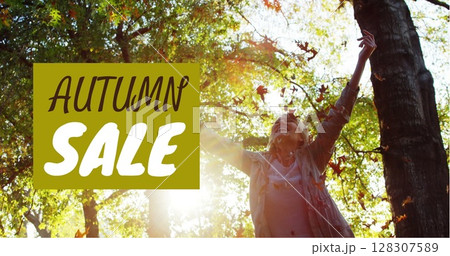 Celebrating autumn sale, joyful woman with arms raised surrounded by forest leaves Celebrating autumn sale, joyful woman with arms raised surrounded by forest leaves 128307589
