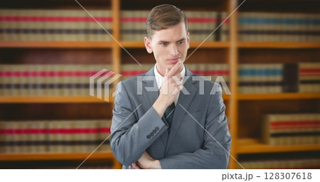 Businessman in suit thinking deeply in front of bookshelf in office 128307618