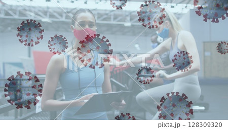 Image of covid-19 cells floating over caucasian women wearing face masks working out Image of covid-19 cells floating over caucasian women wearing face masks working out 128309320