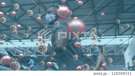 Image of covid-19 cells floating over diverse group wearing face masks working out 128309331
