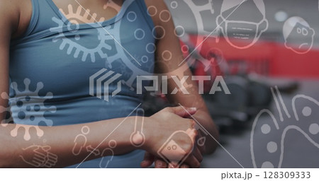 Image of covid-19 icons floating over caucasian woman wiping hands working out 128309333